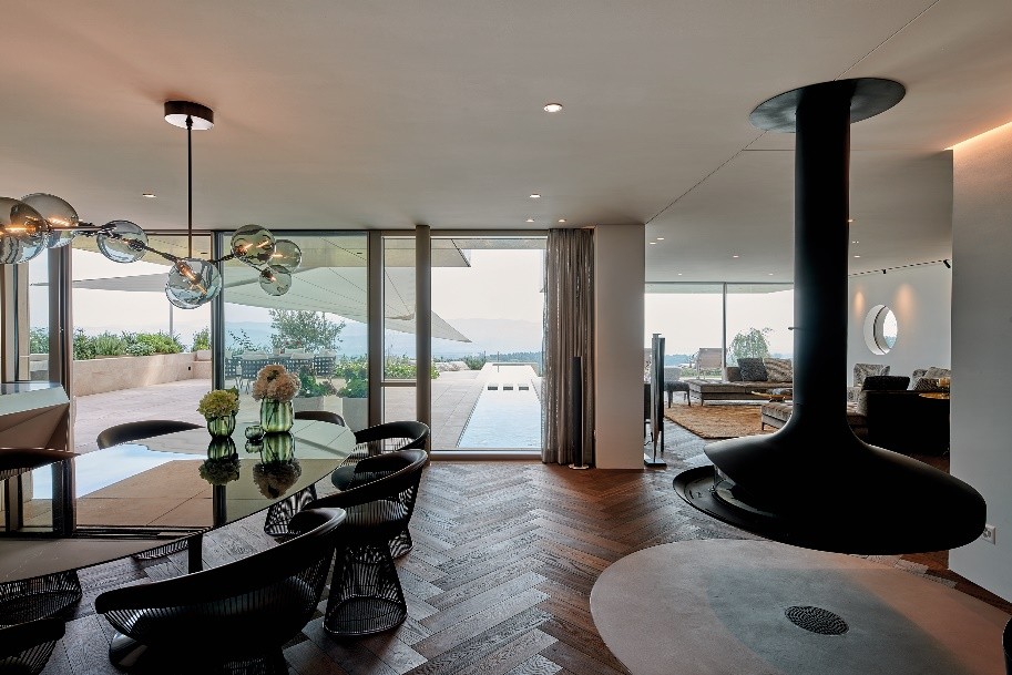 Küche, Ess- und Wohnbereich verschmelzen nahtlos miteinander. Gezielte Designakzente wie ein freischwebender Ofen komplettieren das Interieur. Copyright: VINOVA Architects GmbH Fotograf: Holger Jacob