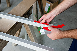 Die Montageplatten werden zusammen mit der Fixierhilfe in die Langlöcher des Wandanschlussprofils gesteckt. Die Klebeschablone wird auf die Montageplatte aufgebracht.Bild: Kermi Duschdesign GmbH