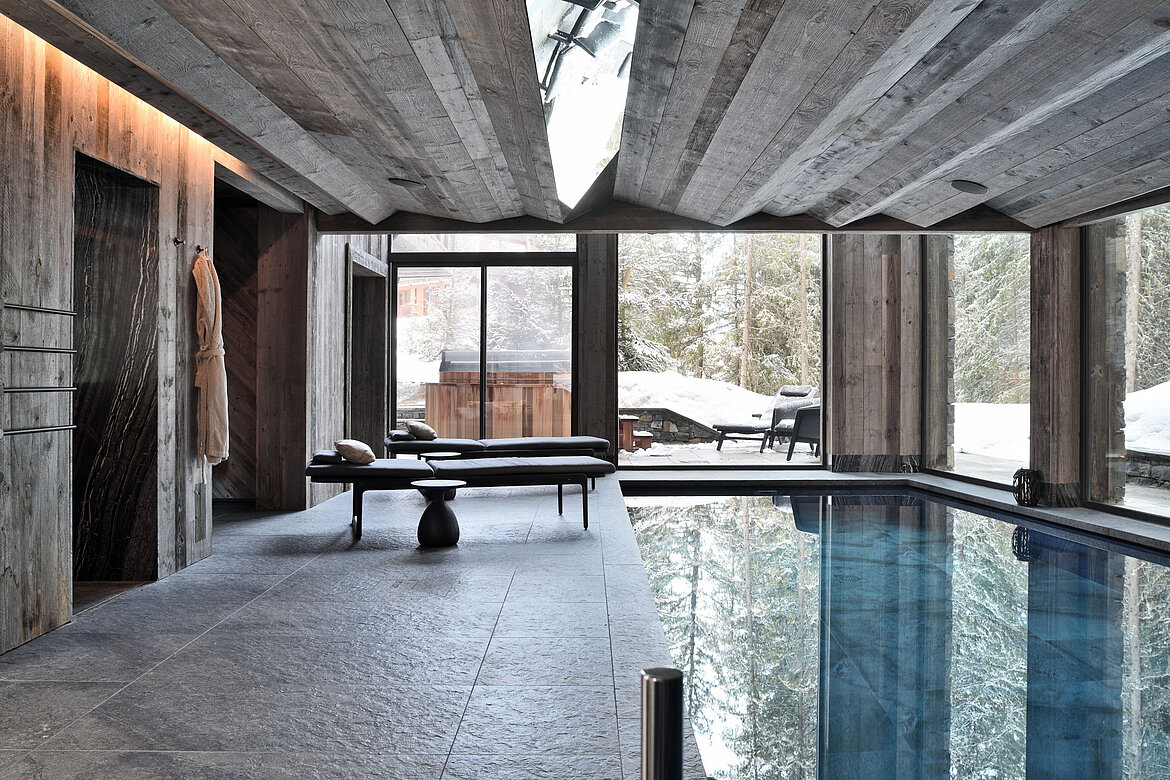 Luxuriöse Entspannungsmöglichkeiten: Pool- und Saunabereich erscheinen wie ein Bestandteil der rauen Alpenlandschaft.
