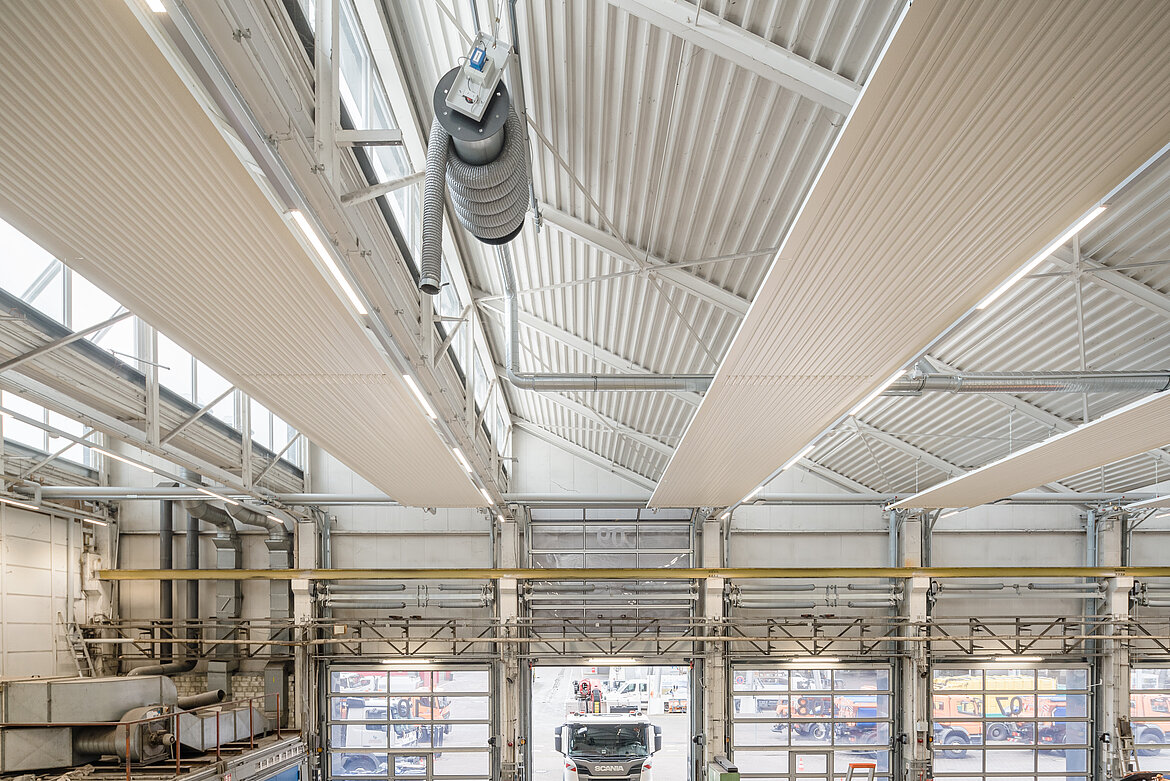 Nach dem Vorbild der Sonnenstrahlung kommt die Wärme der Zehnder Deckenstrahlplatten mit maximaler Effizienz genau dort an, wo sie benötigt wird. Beim häufigen Öffnen und Schließen der großen Tore der Kfz-Werkstatt geht so nur ein minimaler Teil der Wärme nach draußen verloren. Bildquelle: Zehnder Group Deutschland GmbH, Lahr.